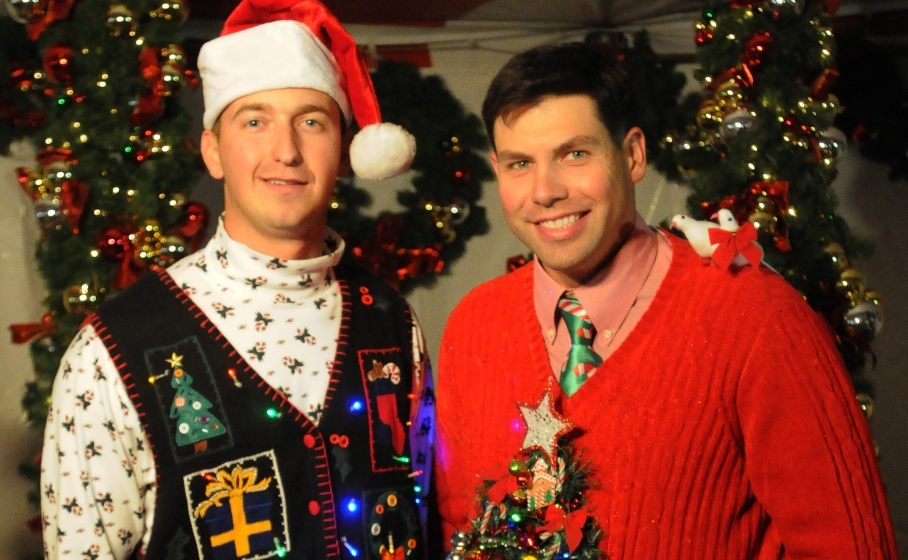 크리스마스 어글리 스웨터를 입고 포즈를 취하고 있는 크리스마스 파티 참석자들